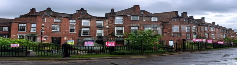 Panoramic view of a row of terraced red-brick Dublin houses on a quiet street, wrought-iron railings and dark front doors with brass numbers, For Sale signs in front gardens, damp morning pavement, overcast grey Irish sky, no people no faces no hands