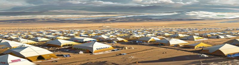Panoramic aerial view of UN-blue tented refugee camp on dusty plain at golden hour, neat rows of white tents stretching to horizon, water tanks and aid trucks visible, distant ridge of low brown hills, no people no faces no hands
